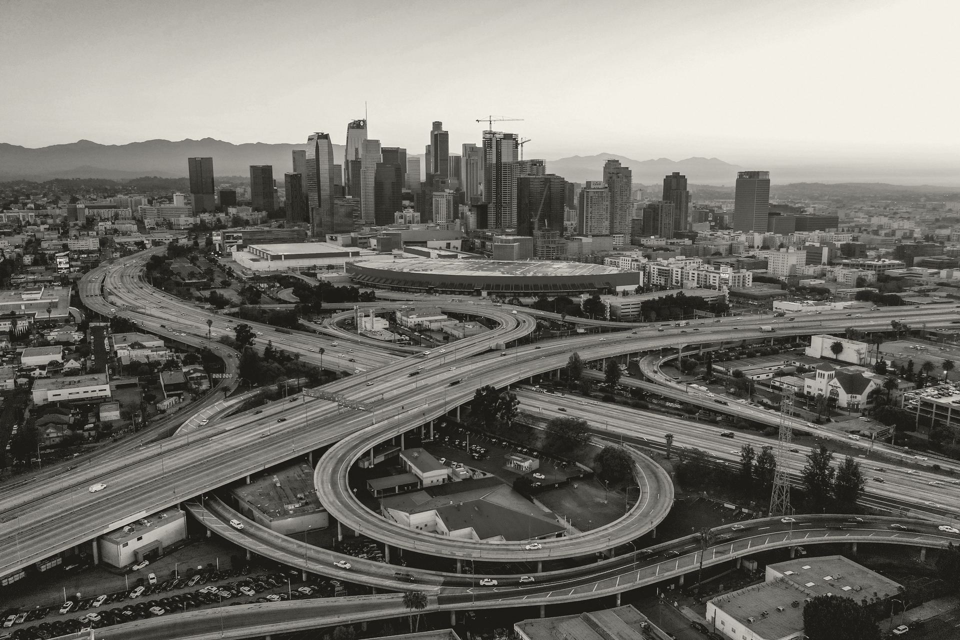 Aerial view of a Los Angeles freeway interchange with the downtown skyline at dawn